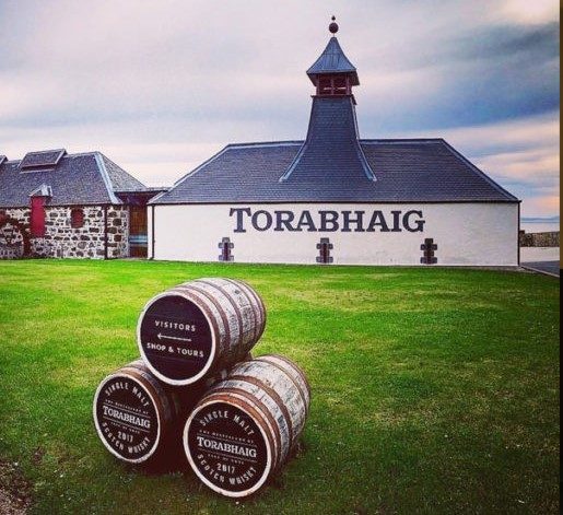 Bâtiment de distillerie Torabhaig avec des fûts en avant sur une pelouse.